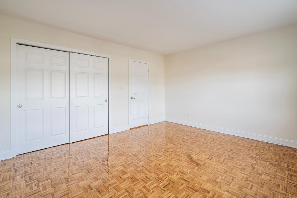 an empty room with a wooden floor and white doors
