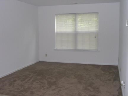 an empty room with a window and a brown floor