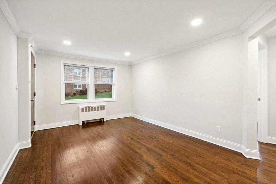 a living room with white walls and wooden floors and a window