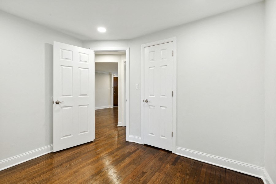 a living room with white walls and wooden floors and three doors