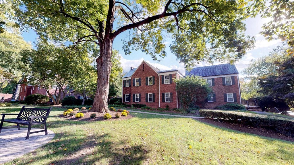 a large brick house with a tree and a bench