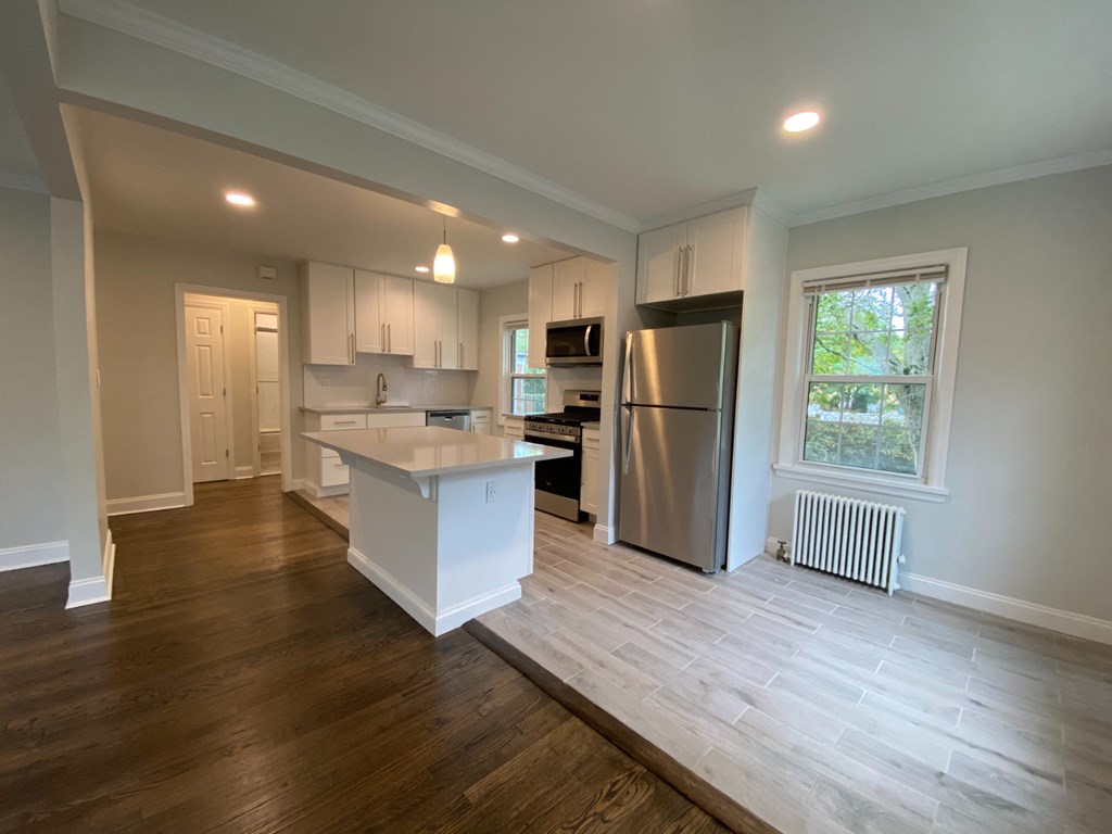 a kitchen with a large island and a stainless steel refrigerator