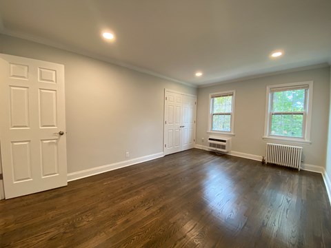 an empty living room with wood floors and white walls
