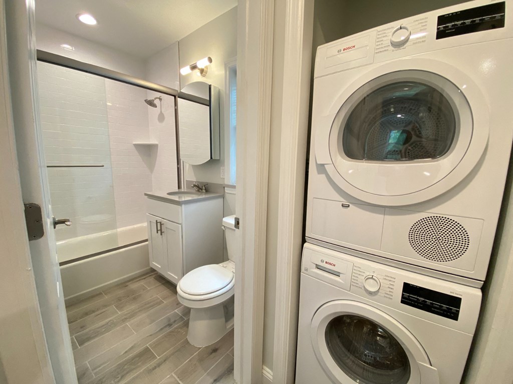 a washer and dryer in a bathroom with a shower and a toilet