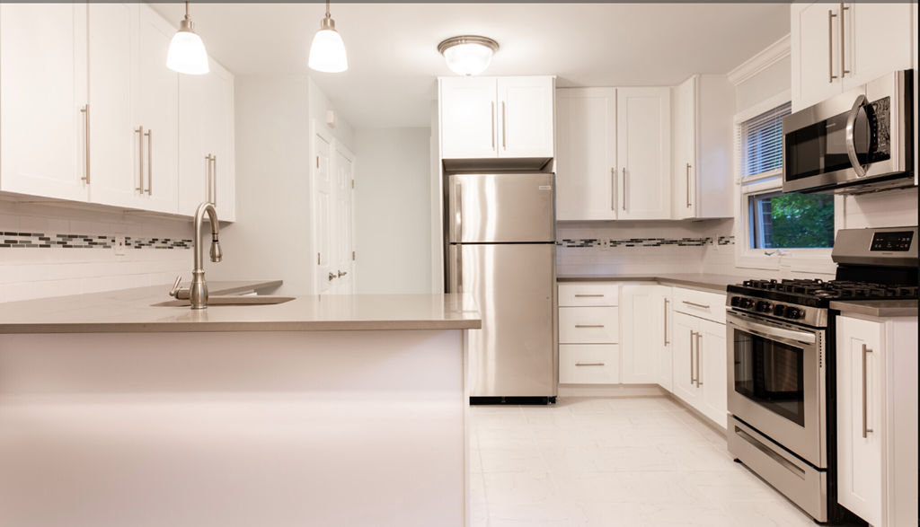 a white kitchen with stainless steel appliances and white cabinets