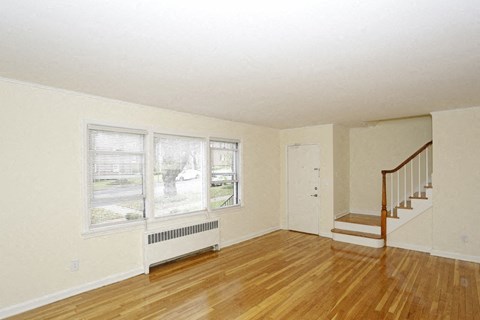 an empty living room with wood floors and a staircase