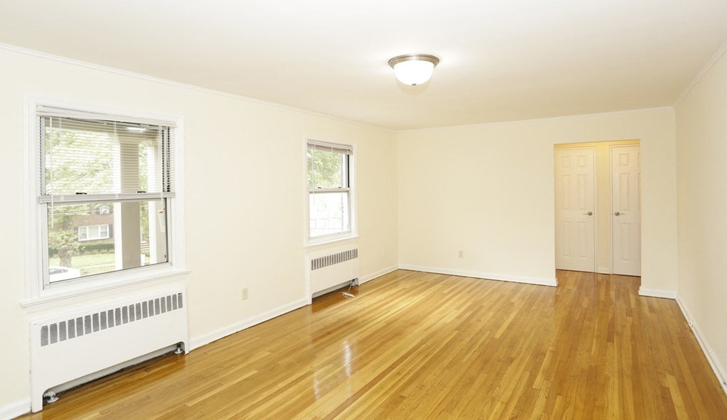 an empty living room with wood floors and a window