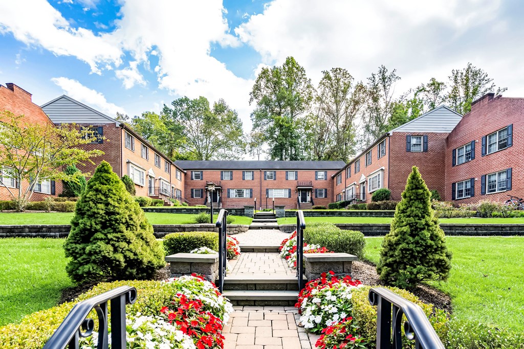 a courtyard with a fountain and flowers in front of an apartment building