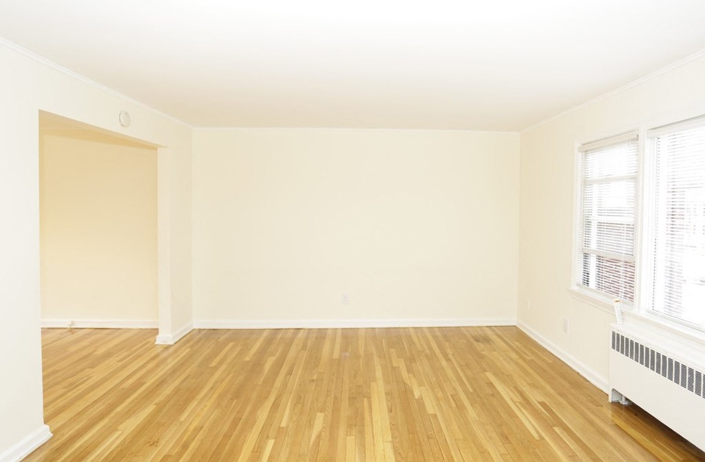 an empty living room with wood floors and white walls
