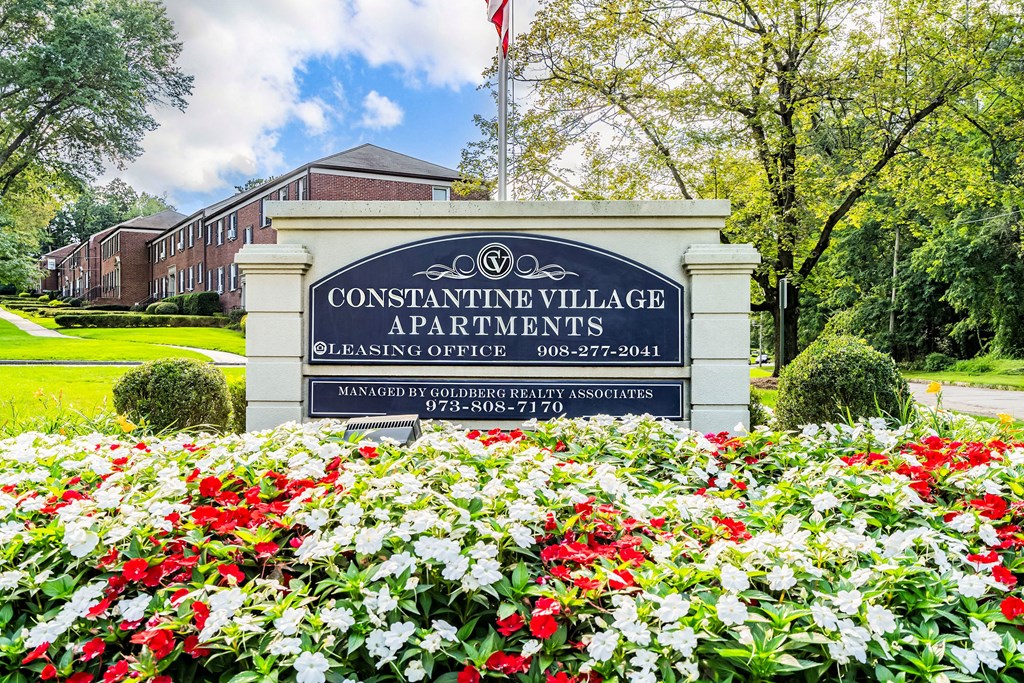 a sign in front of a building with red and white flowers