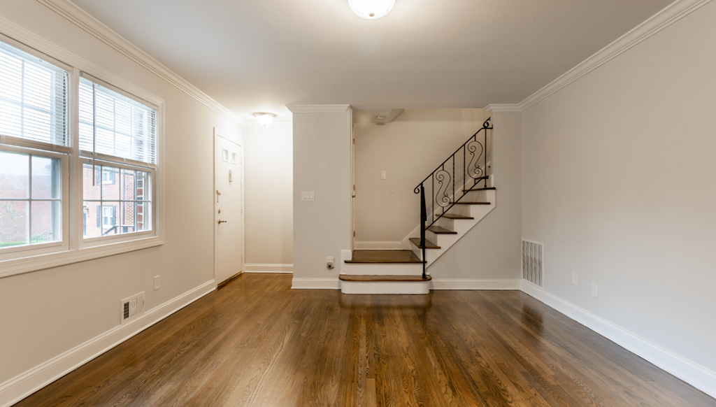 a living room with a staircase and a large window and wooden floors