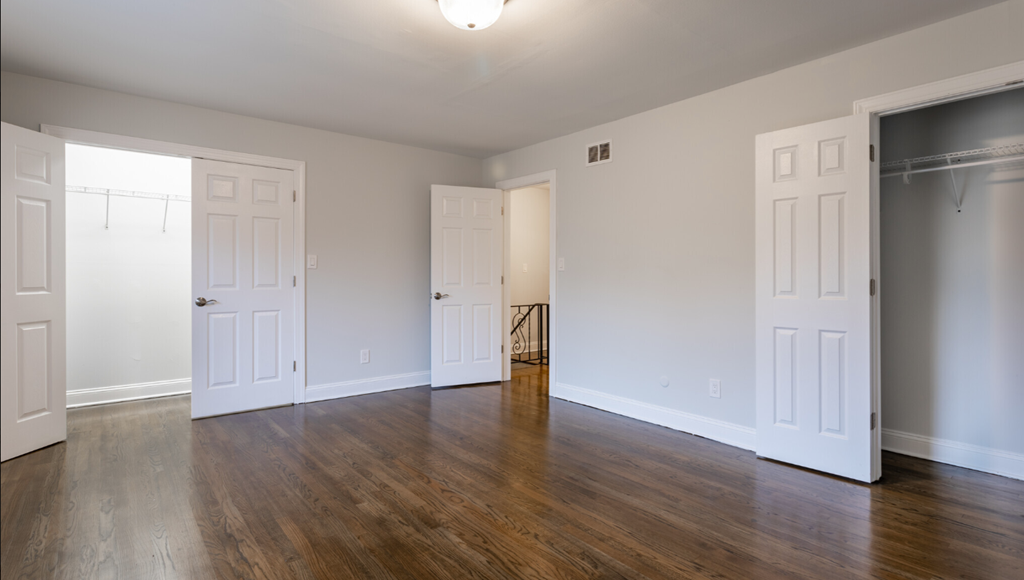 an empty living room with wood floors and white doors