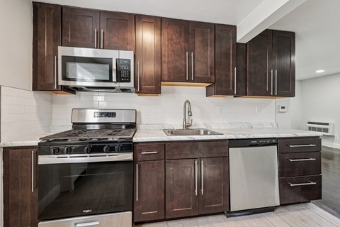 A kitchen with dark brown cabinets and stainless steel appliances.