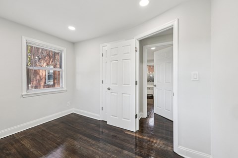 A room with a white door and a window with a view of a brick building.