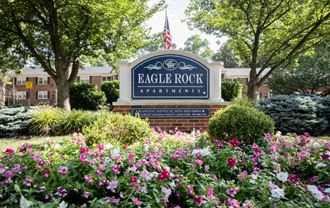 a sign for eagle rock apartments in front of flowers