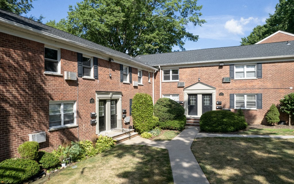 a red brick house with a sidewalk in front of it