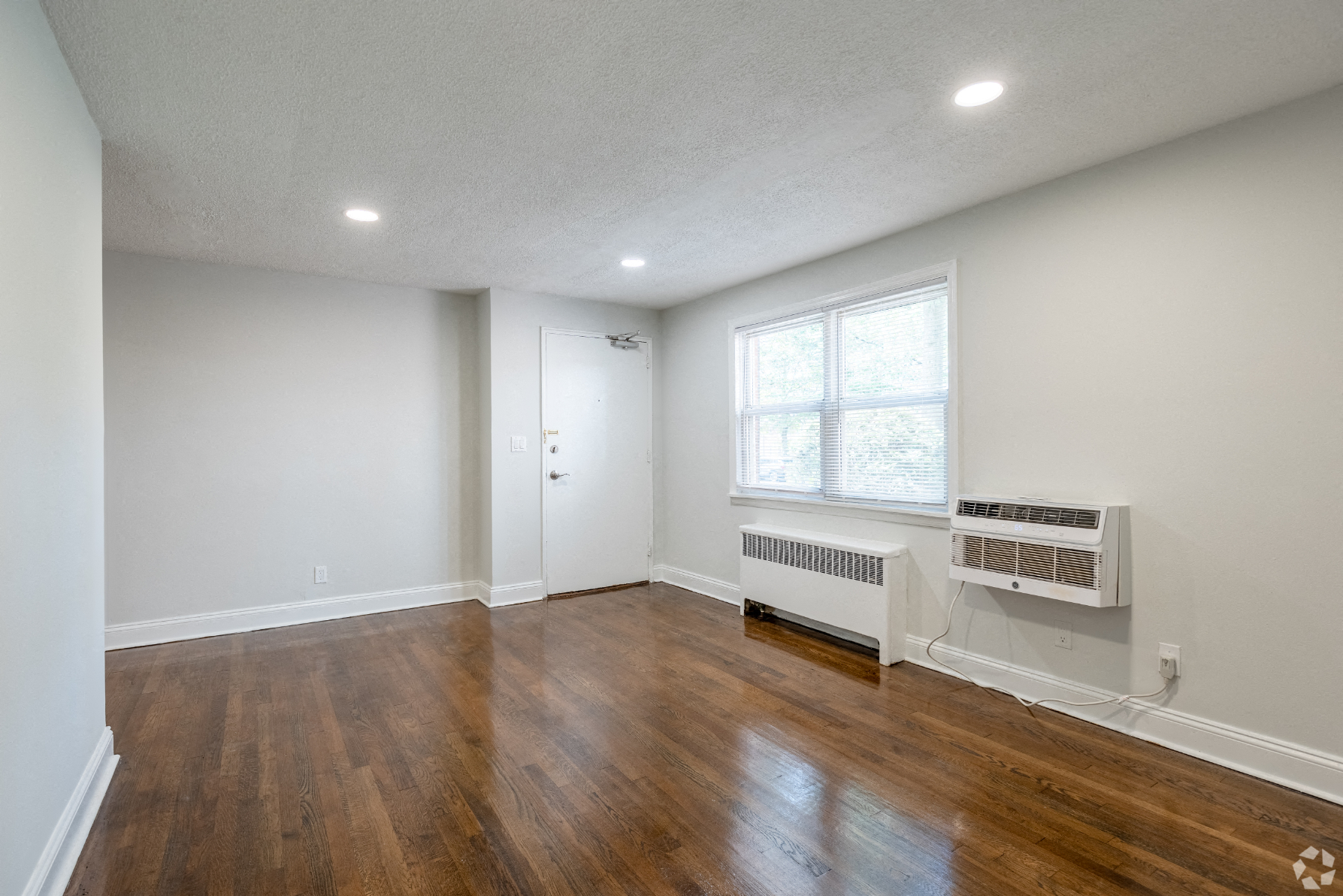 an empty living room with wood flooring and a window
