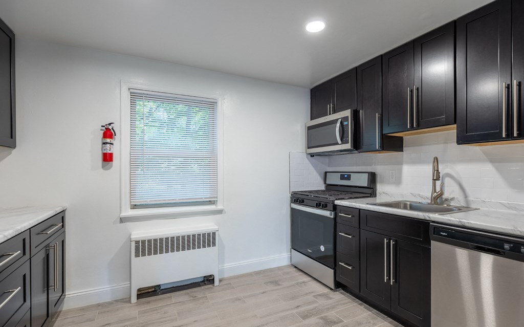 a kitchen with black cabinets and white appliances and a window