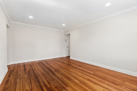 an empty living room with wood floors and white walls