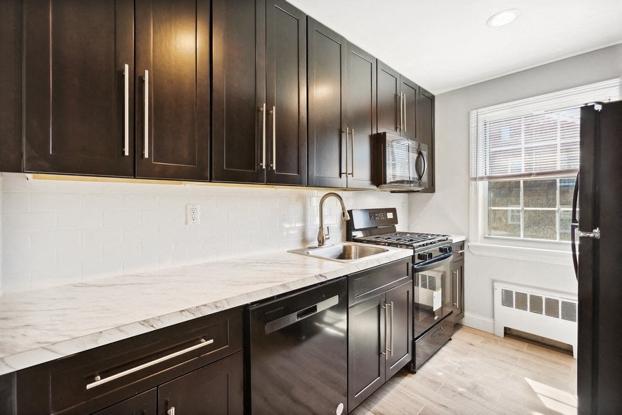 a kitchen with black cabinets and a sink and a window