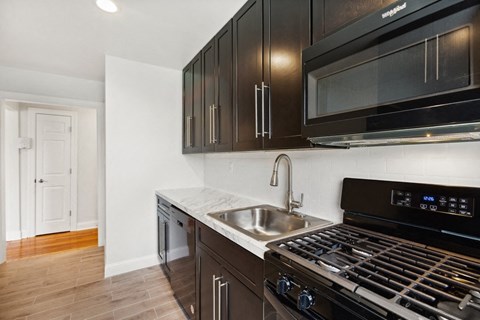 a kitchen with dark wood cabinets and stainless steel appliances and a sink