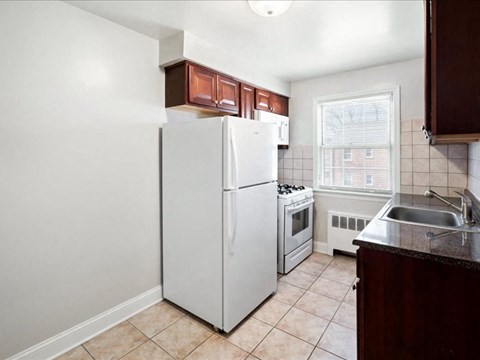 A white refrigerator is in a kitchen with brown cabinets.