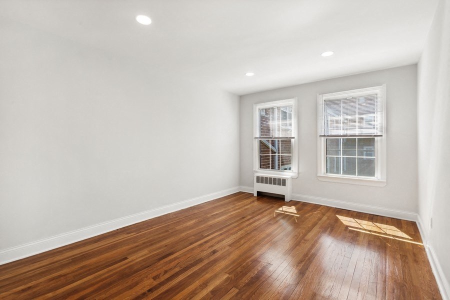 a living room with a hardwood floor and two windows