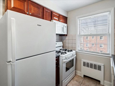 A white Whirlpool refrigerator sits in a kitchen next to a white stove and oven.