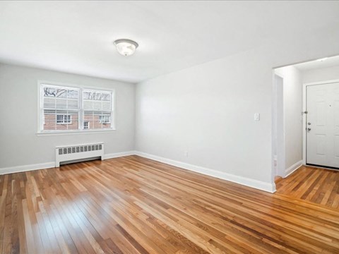 A room with wooden flooring and a window showing a building outside.