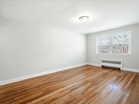 A room with wooden flooring and a window with blinds.