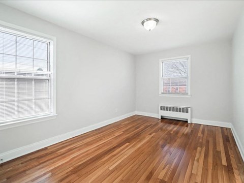 A room with wooden flooring and a window with blinds.