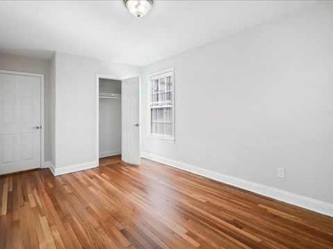A room with wooden flooring and a window with blinds.