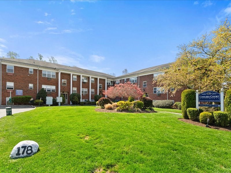 A grassy area in front of a building with a sign that says Sheridan Court.