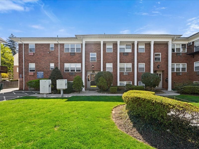 A large brick building with a green lawn in front.