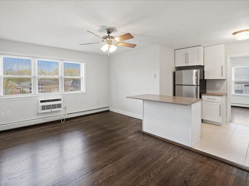 A kitchen with white cabinets and a wooden floor.