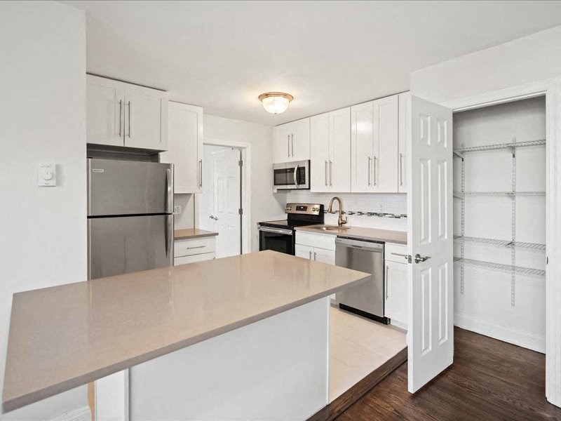 A kitchen with white cabinets and a wooden island.