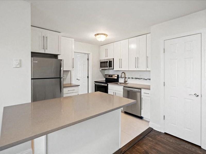 A kitchen with white cabinets and appliances.