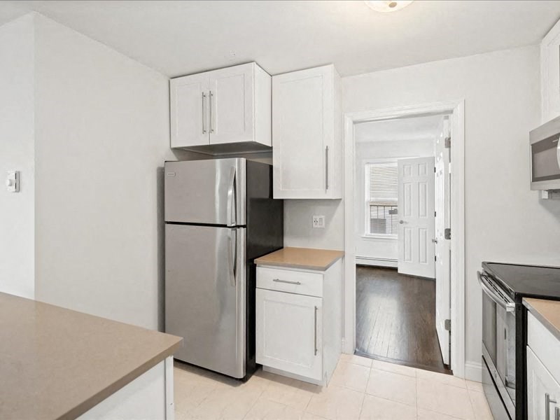 A kitchen with a refrigerator, oven, and microwave.