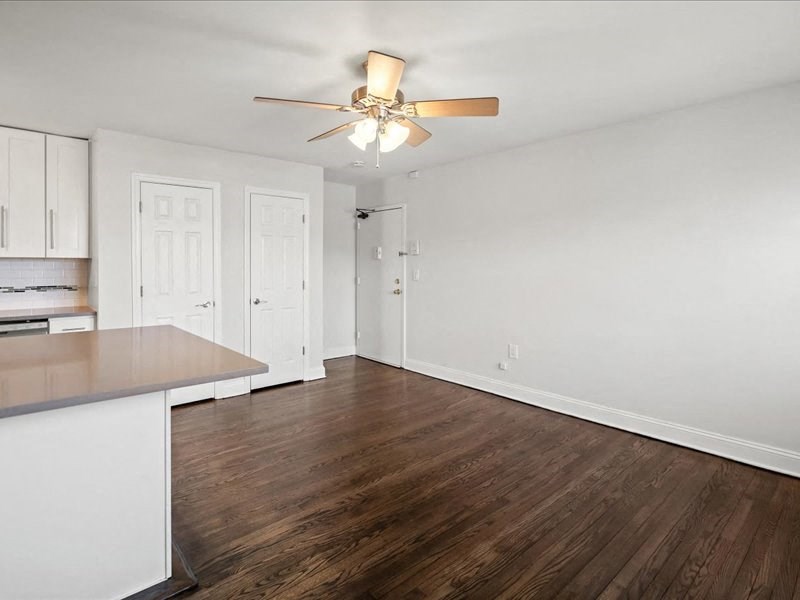 A room with a brown wooden floor and a ceiling fan.
