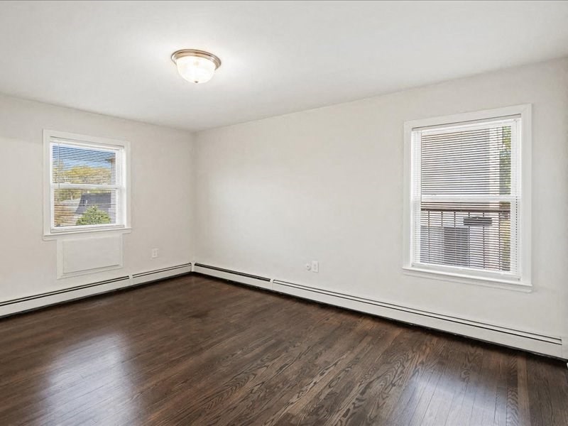 A room with a window and a wooden floor.