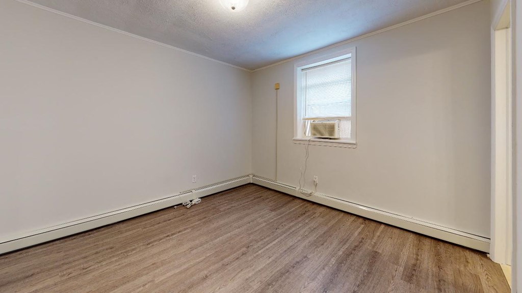 the living room of an empty home with wood floors and a window