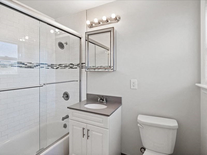 A white bathroom with a glass shower stall and a toilet.