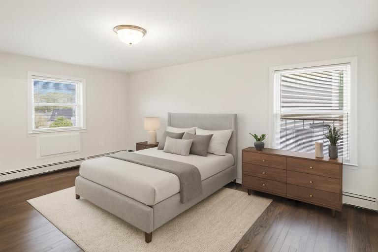 A bedroom with a large bed, a nightstand, and a window with blinds.