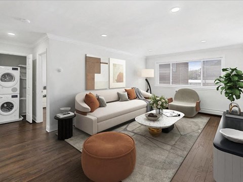 A modern living room with a white sofa, a brown ottoman, and a grey rug.