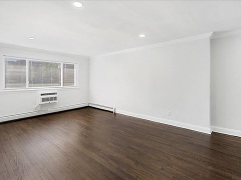A room with wooden floors and a window with blinds.