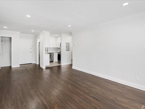 A spacious room with wooden floors and white walls.