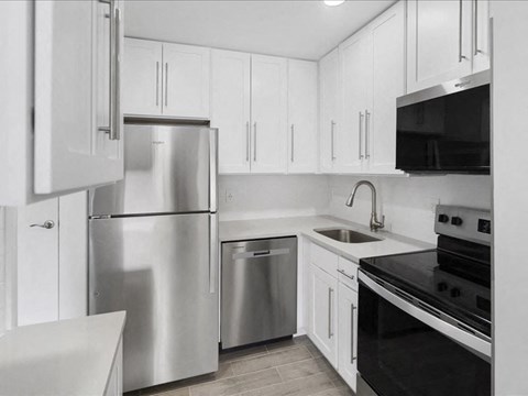 A modern kitchen with white cabinets and stainless steel appliances.