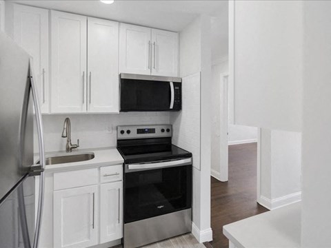 A modern kitchen with white cabinets and stainless steel appliances.