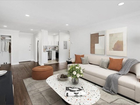 A modern living room with a white couch, a coffee table, and a large painting on the wall.