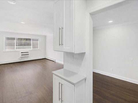 A white kitchen with wood flooring and a window.
